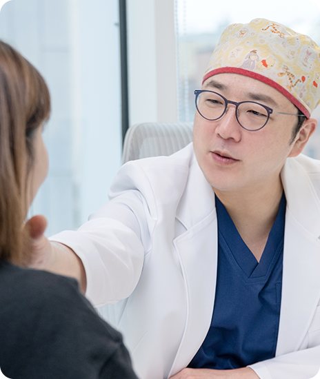 수술모를 쓴 의사가 여성 환자의 얼굴을 살피며 상담하는 모습