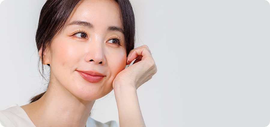 손을 볼에 대고 옆을 바라보며 미소 짓는 여성 모델