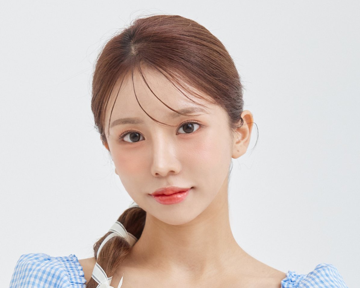 연회색 배경, 파란 체크 블라우스에 머리를 묶은 여성 모델 정면 상반신