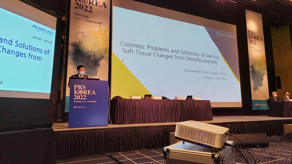 ‘Cosmetic Problems and Solutions of Various Soft Tissue Changes from Mandibuloplasty’ 화면 앞 PRS KOREA 2022 연단에서 발표하는 임종우 원장