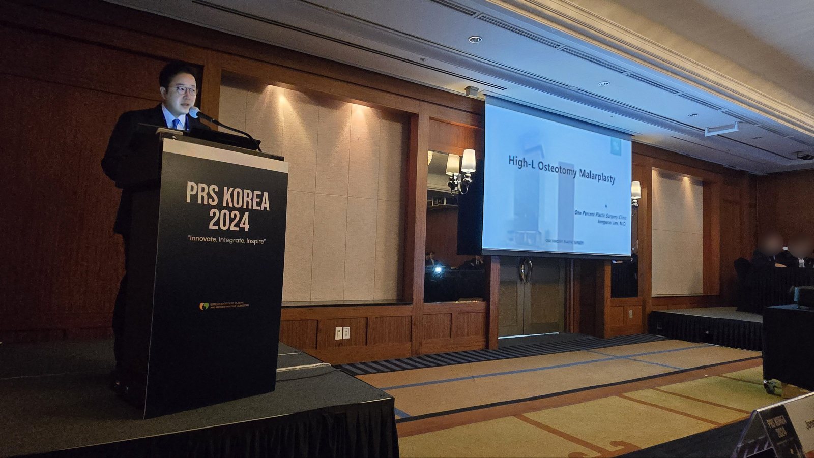 ‘High-L Osteotomy Malarplasty’ 화면 옆 PRS KOREA 2024 연단에서 발표하는 임종우 대표원장