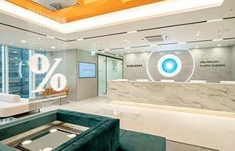 일퍼센트 둘러보기 — % 로고 벽과 대리석 안내 데스크, 초록 소파 대기 공간